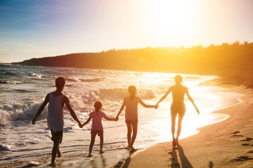 Luxury family travel – family holding hands on a sunset beach

