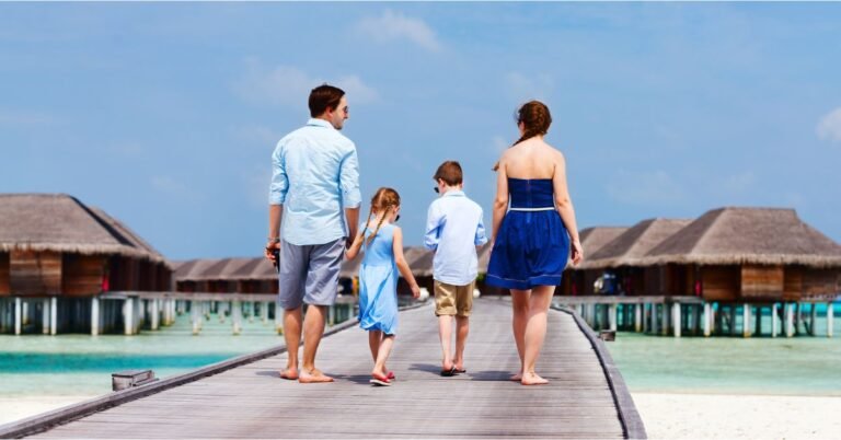 family walking along a wooden pier towards luxury overwater bungalows in the maldives