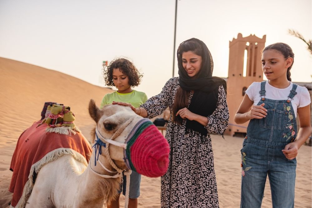 family petting a camel in the dubai desert