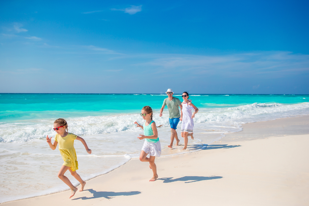Parents and children walking along a luxury resort beach in the Maldives